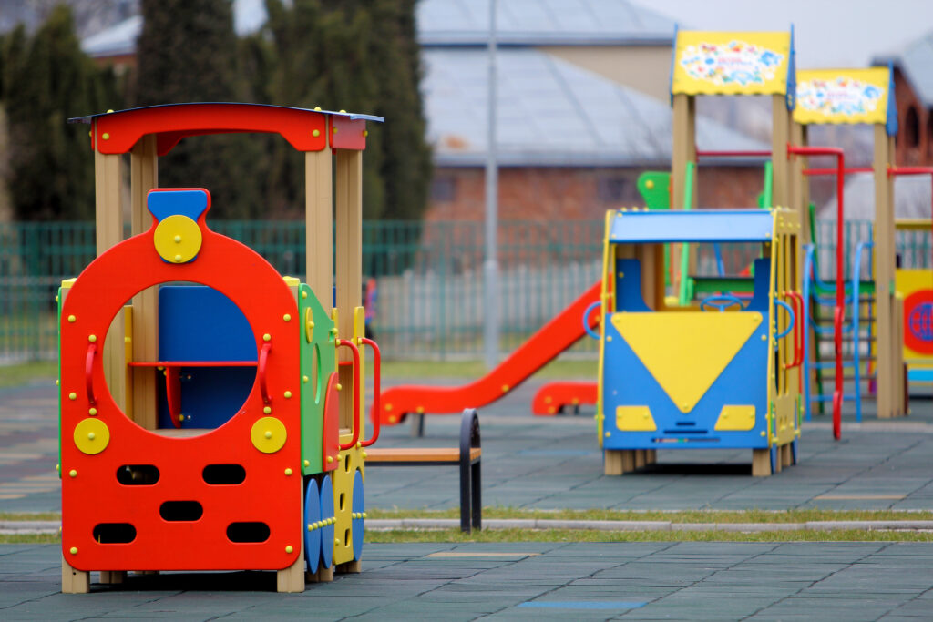 bright colorful big toy cars on nursery playground with soft rubber flooring on bright sunny summer day. perfect place for children activities and recreation outdoors.