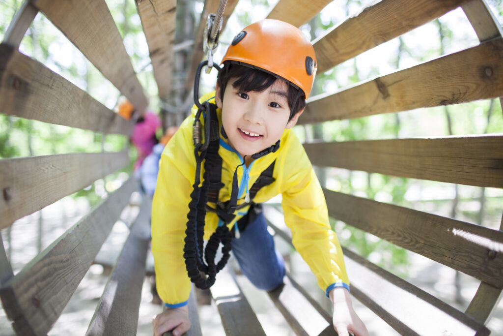 little chinese boy playing in tree top adventure park